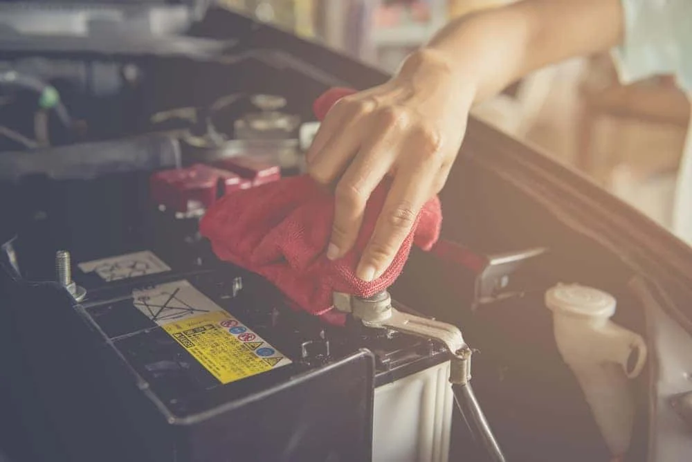 Technician cleaning a car battery at Albany Motorcars