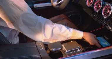 Driver reaching for a phone in the front console of an EQ vehicle