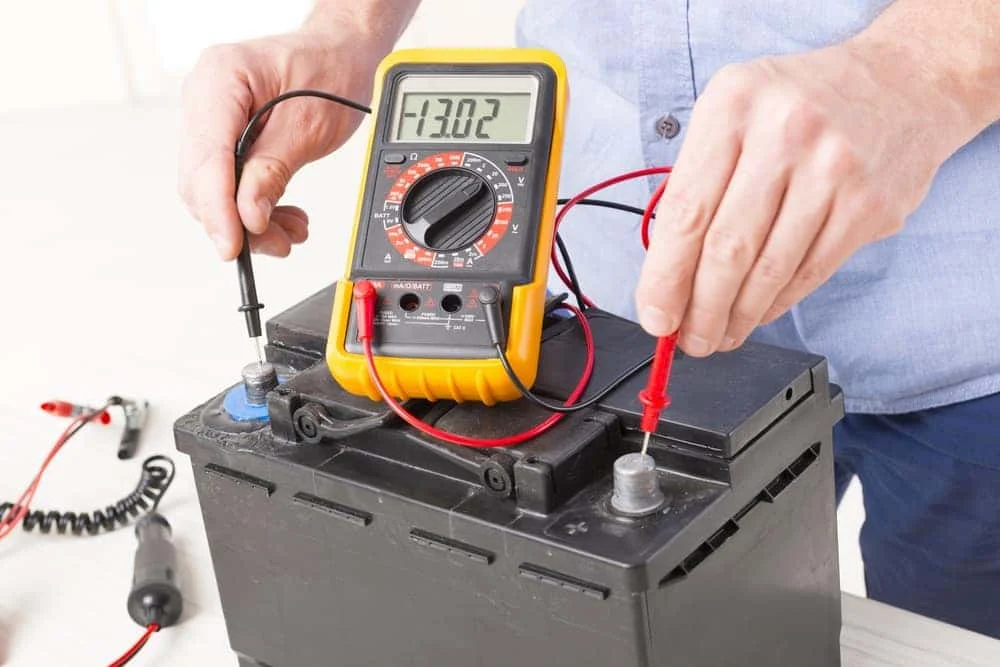 Technician checking car battery voltage with a multimeter