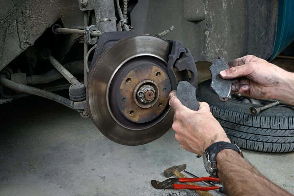 Technician replacing a worn brake pad